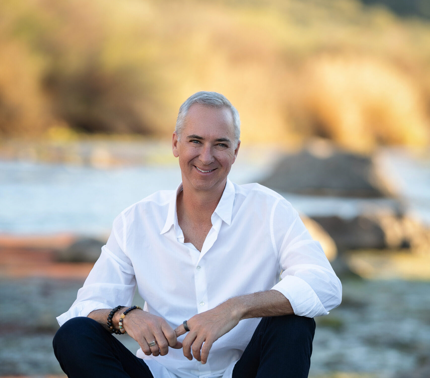 Cameron Herold, founder of COO Alliance, smiling outdoors while holding his book The Second in Command